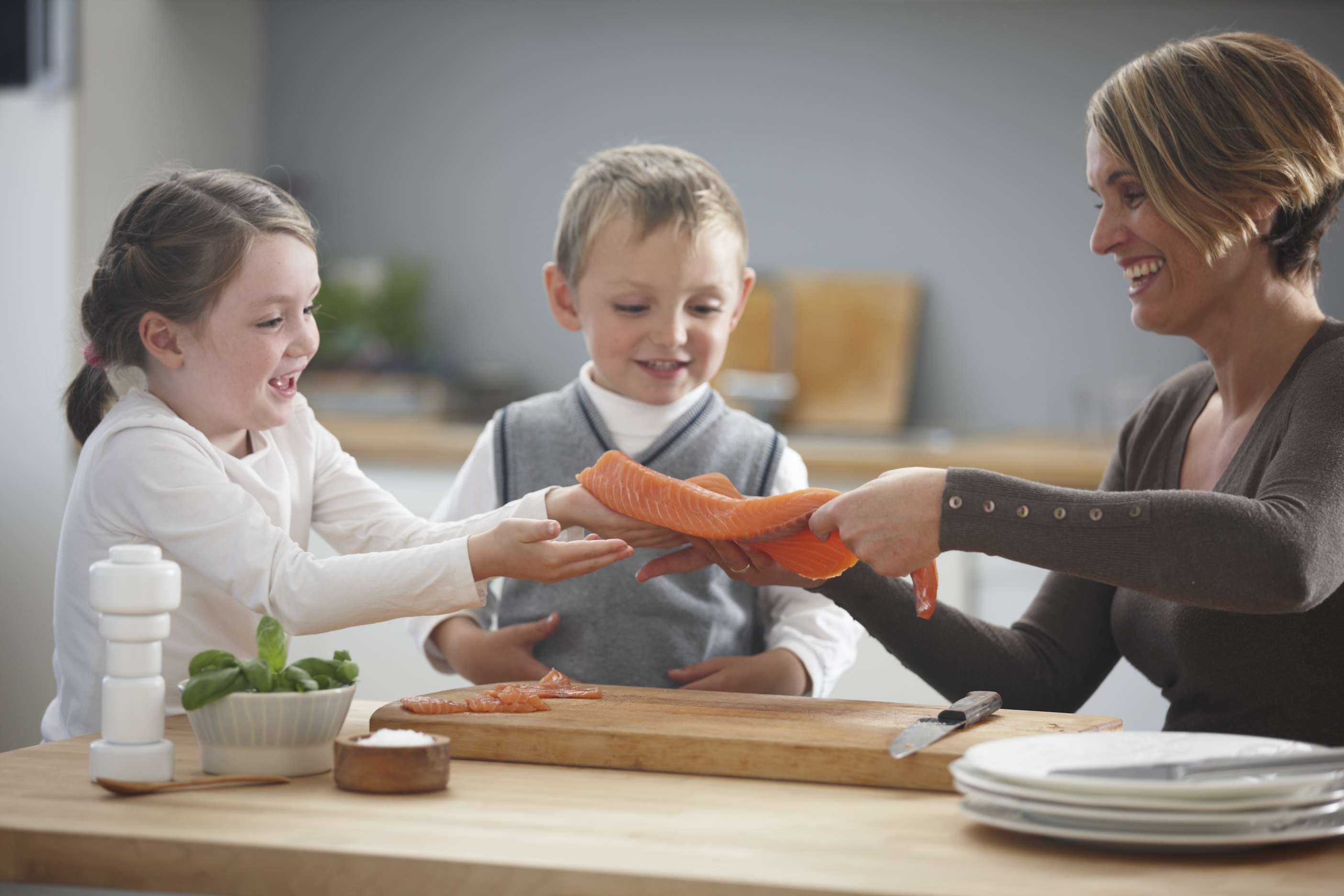 Barn på kjøkkenet med mor prøver laks